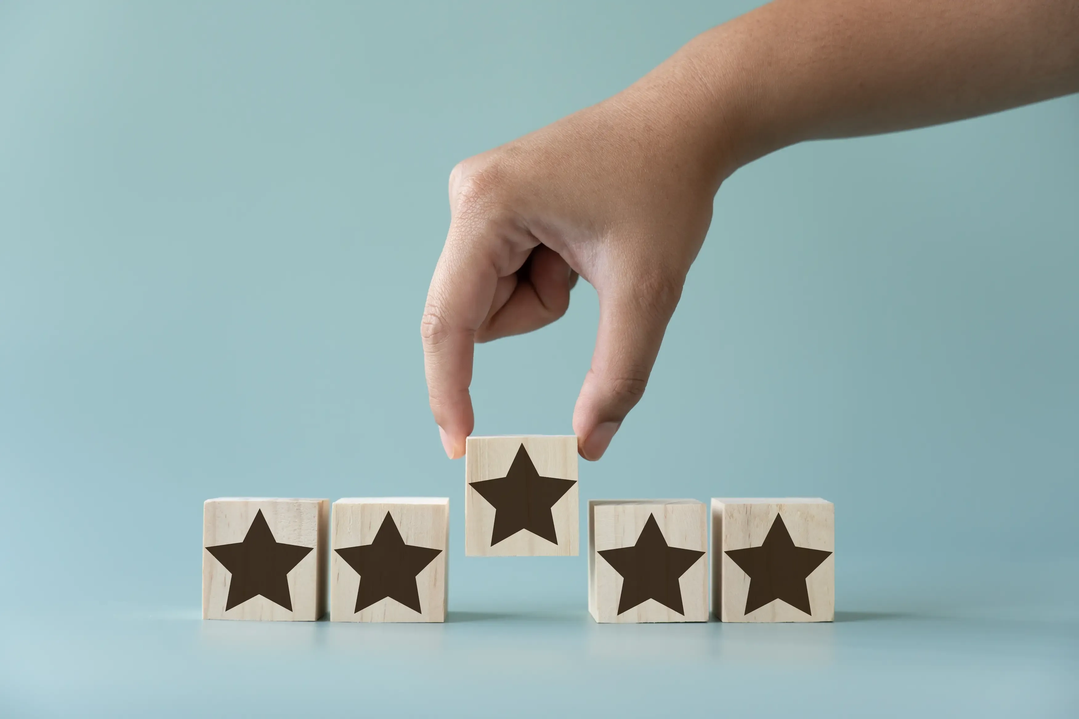 Dłoń wyciągająca trzeci drewniany klocek z symbolem gwiazdki